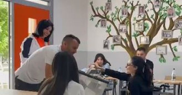 E buzëqeshur hedh votën në kutinë e votimit, vajza me