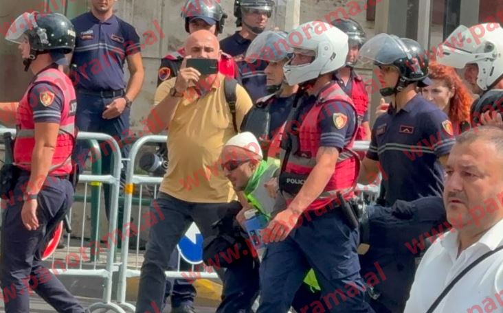 Protest organizer Arben Kola is escorted and dragged away by police